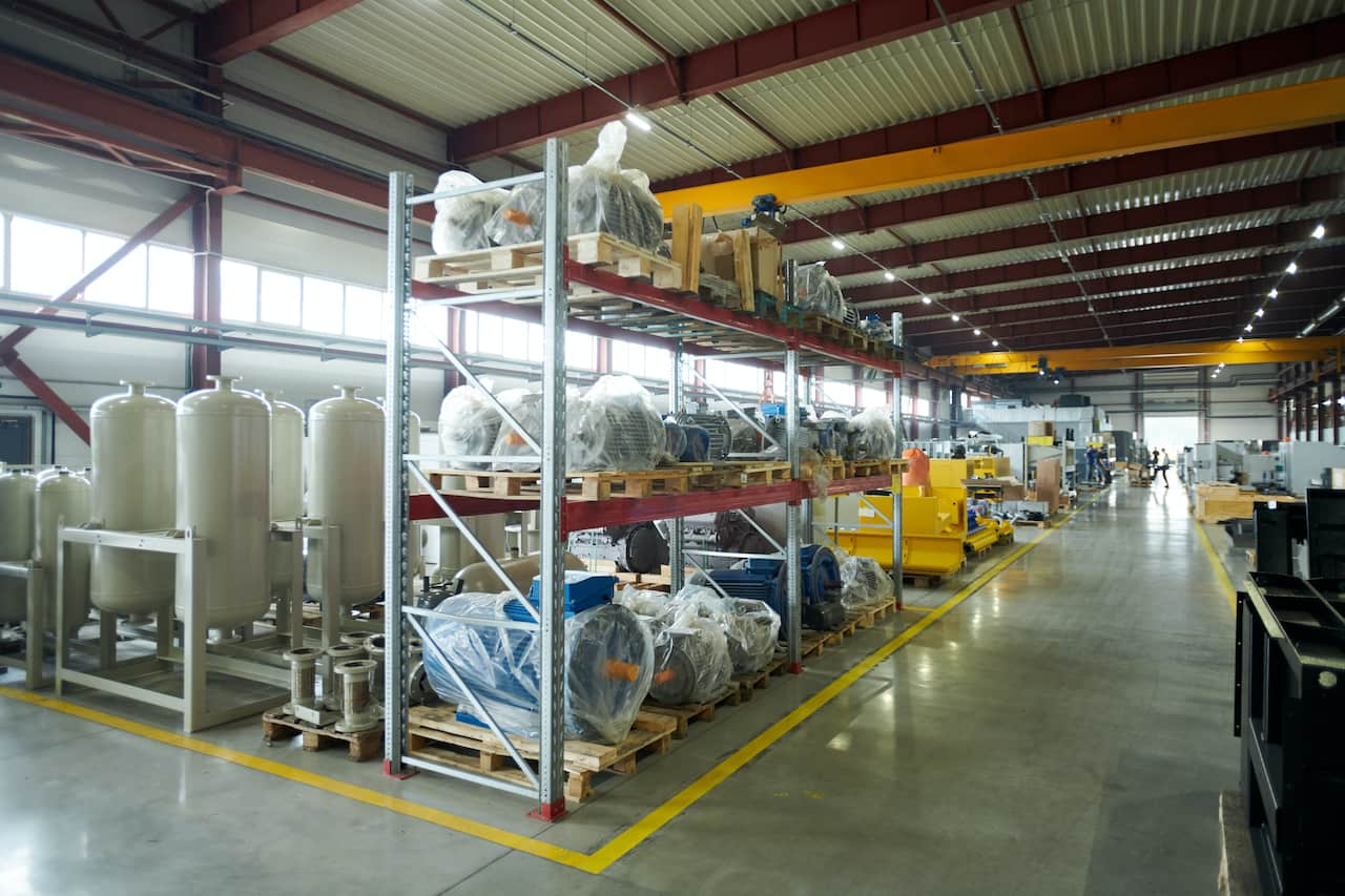 The inside of a warehouse with shelving and industrial equipment